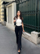 a lady wears a white top with ruffle design and black skinny pants